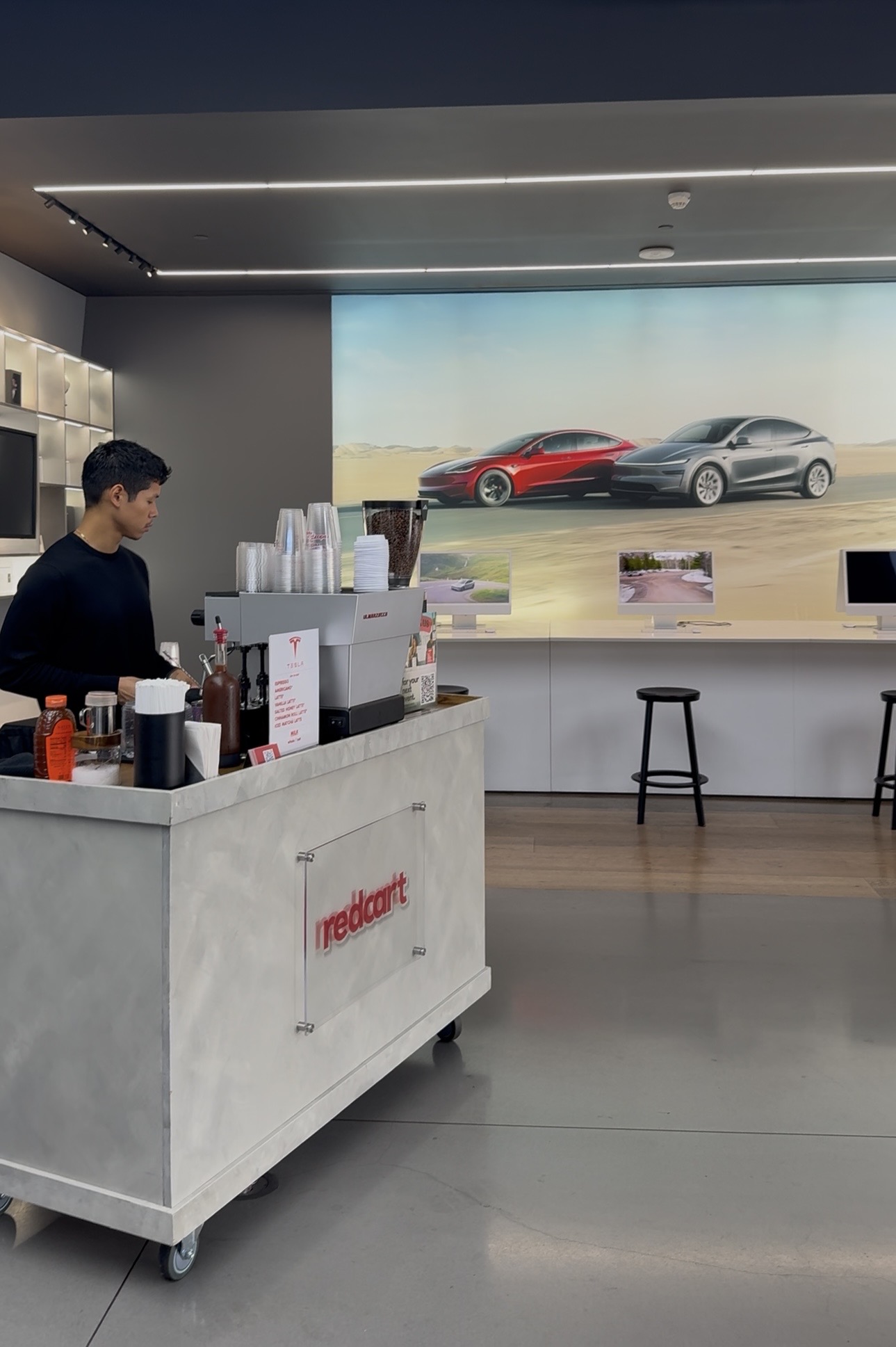 Redcart mobile espresso cart serving inside a Tesla showroom with branded cart and barista